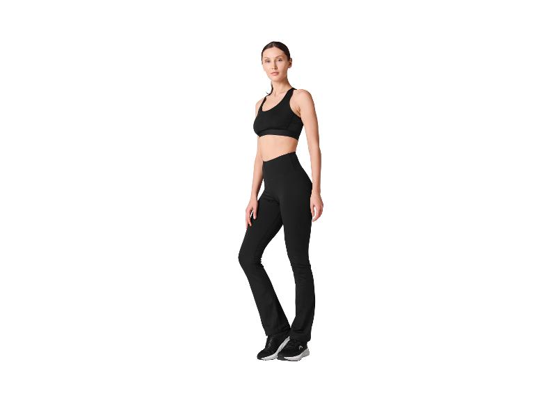 Femme en tenue de sport noire, composée d'un soutien-gorge de sport et d'un legging.