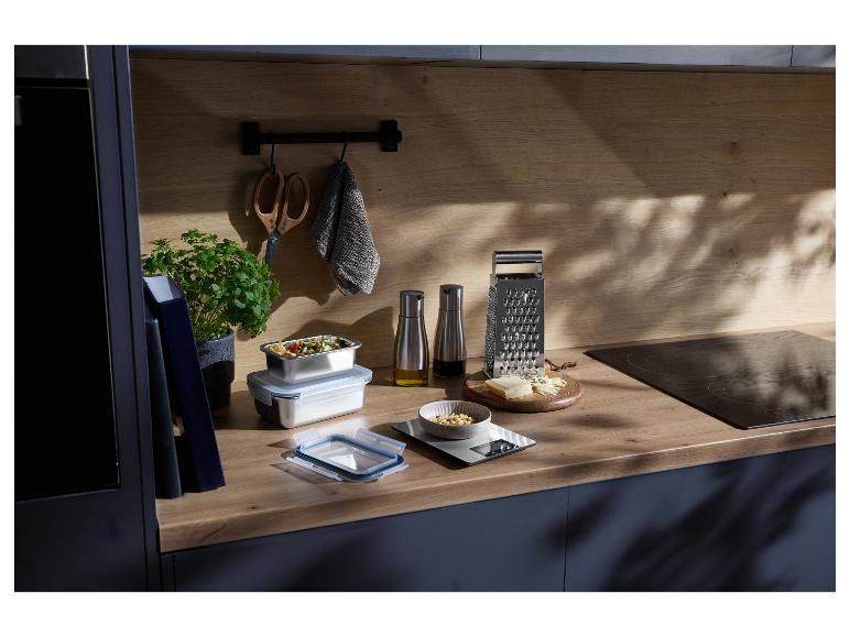 Comptoir de cuisine avec des récipients alimentaires, une râpe, du fromage et des essentiels de cuisine.