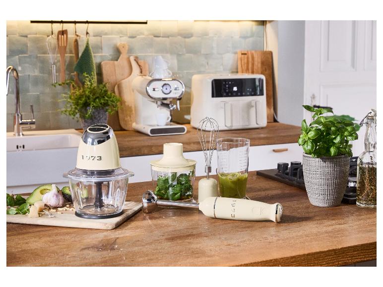 Appareils électroménagers de cuisine rétro : hachoir, mixeur plongeant et autres accessoires sur une table en bois.