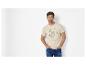 Homme en t-shirt beige clair avec motif tortue et texte, jean bleu