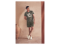 Homme en t-shirt et short olive, portant des baskets claires.