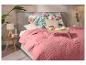 Chambre avec un couvre-lit rose, des oreillers à motifs floraux et un plateau de petit-déjeuner en bois.