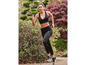 Une femme en soutien-gorge de sport noir et leggings court dans la forêt.