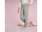 Une femme porte un pantalon de survêtement vert avec un petit logo.