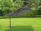 Un parasol gris avec un bras, installé sur une pelouse.