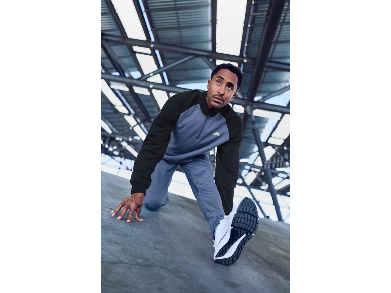 Homme en sweat et pantalon de sport, en position de départ.