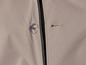 Détail d'une veste beige avec un bouton et une boutonnière.