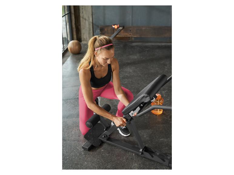 Femme ajustant un banc de musculation dans une salle de sport.