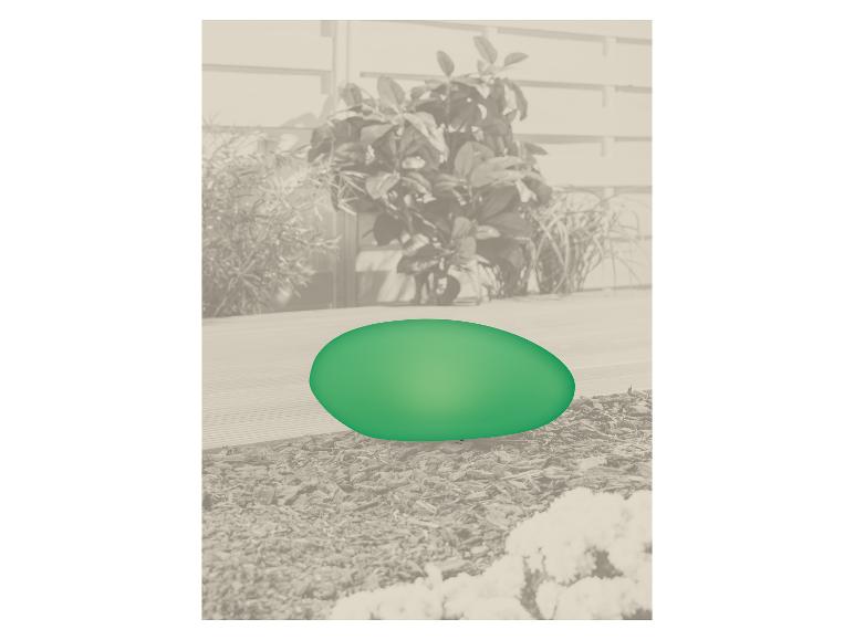 Œuf décoratif vert sur une terrasse avec des plantes en arrière-plan.