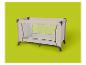 Lit de voyage pliable beige avec côtés en maille sur fond vert lime.