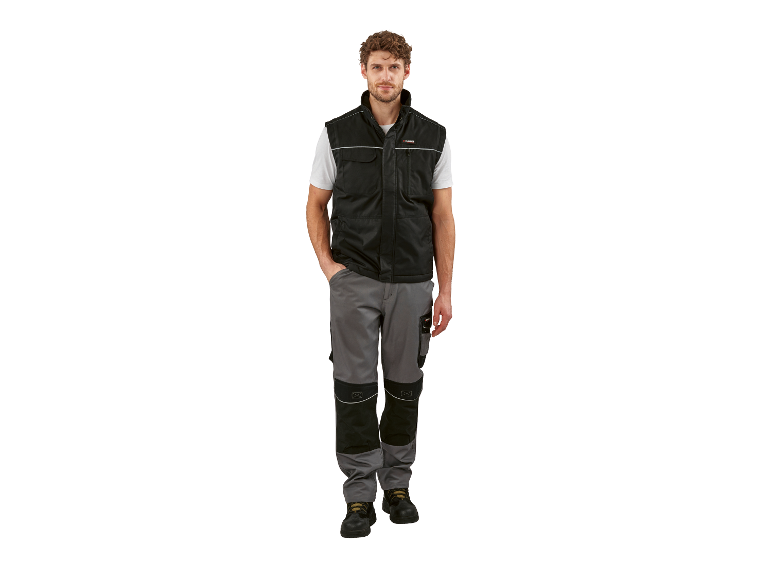 Un homme porte un gilet noir Parkside et un pantalon de travail gris.