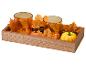Plateau en bois automnal avec deux bougeoirs en verre orange, feuilles d'érable et citrouilles.