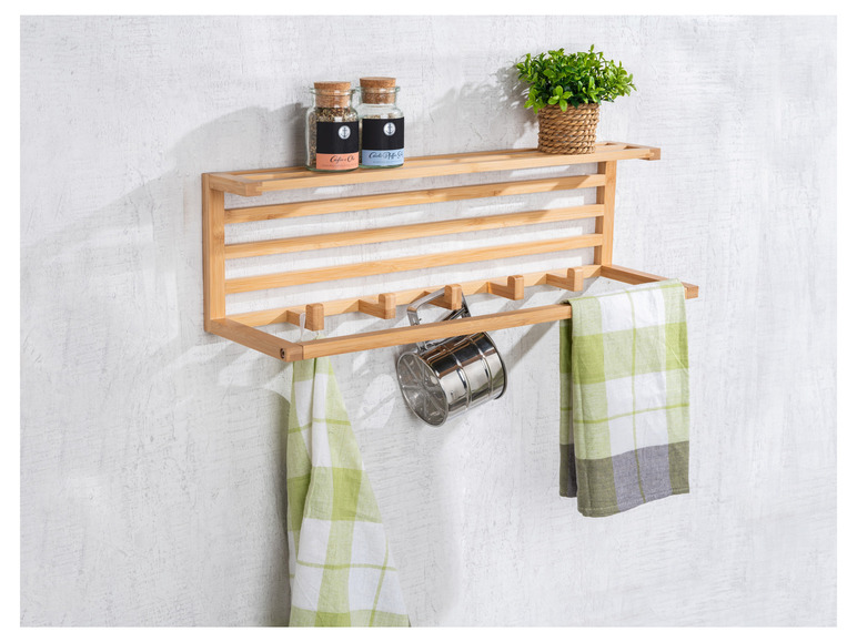 Une étagère murale en bois avec des serviettes, une passoire et des pots à épices.