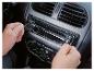 Mains installant un autoradio avec fonction Bluetooth et commandes de climatisation.