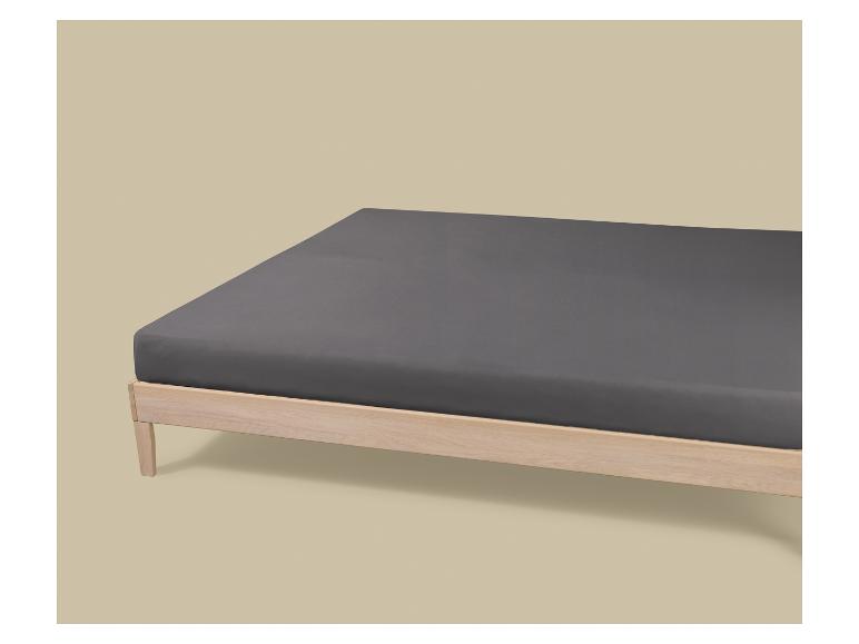 Lit en bois avec un matelas gris foncé sur fond beige.