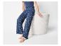 Femme en pantalon de pyjama bleu foncé à imprimé marguerites et t-shirt assorti, assise.