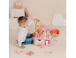 Garçon jouant avec une station de soins pour poupée rose avec bébé et accessoires.