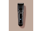 Tondeuse à cheveux noire avec bouton d'alimentation et indicateur de charge.