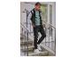 Un homme avec un pull noir, un pantalon noir et des chaussures blanches tient une planche à roulettes.
