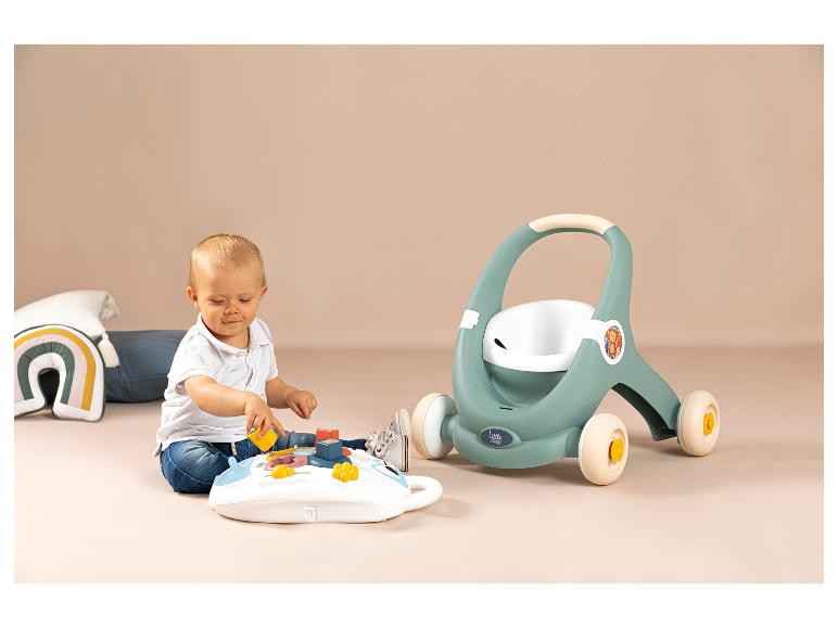 Bébé jouant avec une table d'activités et un trotteur Little Smoby en arrière-plan.