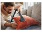 Un homme nettoie un coussin avec un nettoyeur vapeur Silvercrest.