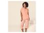 Femme en t-shirt pêche et pyjama capri rayé, souriante.