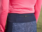 Un gros plan de l'arrière d'un pantalon bleu foncé avec un imprimé abstrait et une poche zippée.