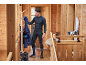 Homme en sous-vêtements thermiques de ski noirs, prenant une veste bleue, avec des chaussures de ski et un snowboard.