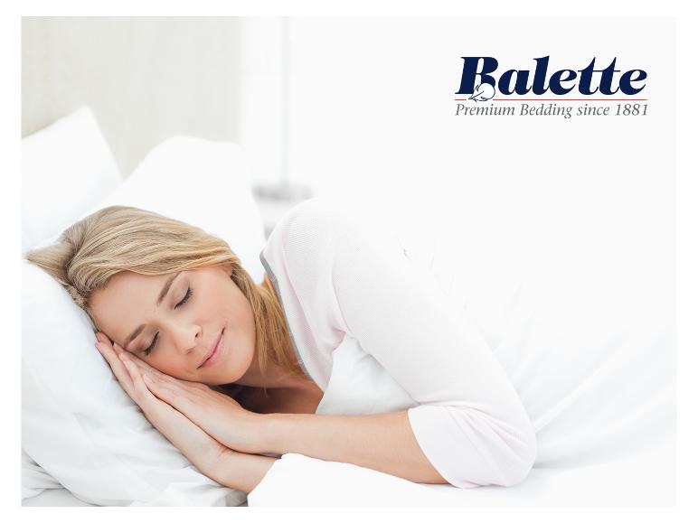 Femme dormant sur un oreiller et une couette blancs, avec le logo Balette Premium Bedding.