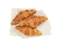 Trois croissants dorés au beurre sur une serviette claire.