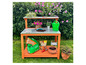 Table de jardin avec de la terre, des plantes et un arrosoir.