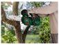 Une personne utilise une tronçonneuse Parkside pour couper une branche d'arbre.