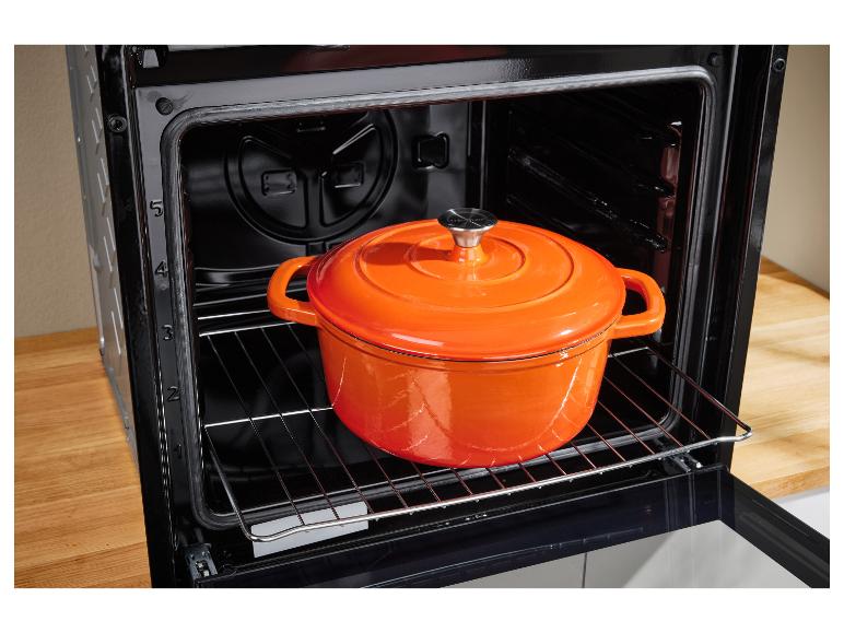 Une cocotte orange en fonte sur la grille d'un four Silvercrest.