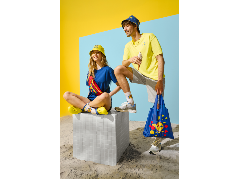 Deux personnes en tenue décontractée d'été, avec des chapeaux bob, des t-shirts et des sacs de courses.