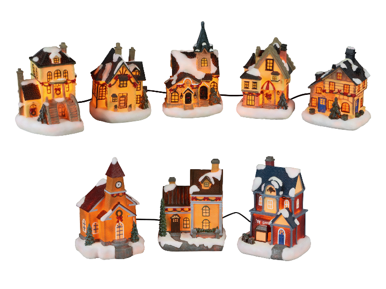 Une guirlande de maisons de village de Noël illuminées avec des toits enneigés.