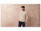 Homme portant un pull beige et un jean bleu