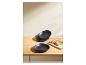 Assiettes noires empilées et une assiette individuelle avec du pain sur une table en bois.
