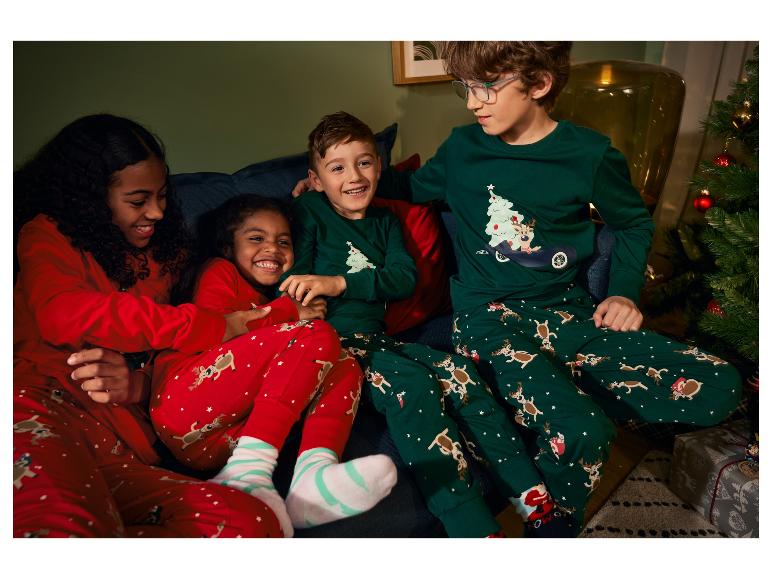Des enfants portant des pyjamas de Noël avec des motifs de rennes et d'arbres de Noël.