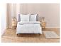 Une parure de lit blanche avec un motif géométrique, deux taies d'oreiller et un tapis