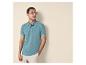 Homme en polo bleu-vert et short beige, avec des lunettes de soleil, regardant à droite.