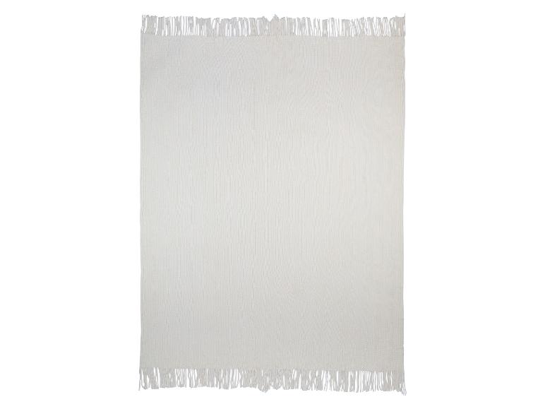 Une couverture en tricot crème avec des franges.