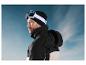 Un homme porte une veste de ski noire avec un bandeau CRIVIT blanc et des lunettes de ski.