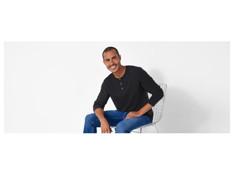 Un homme portant un t-shirt noir à manches longues et un jean bleu.