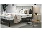 Un lit gris avec un matelas Emma et un couvre-lit rayé.