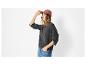 Femme en pull gris, jean et casquette rose, la main sur la visière.