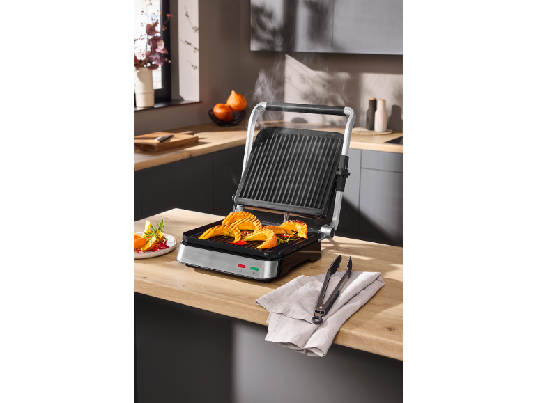Gril de contact électrique avec du potiron grillé sur un plan de travail de cuisine.