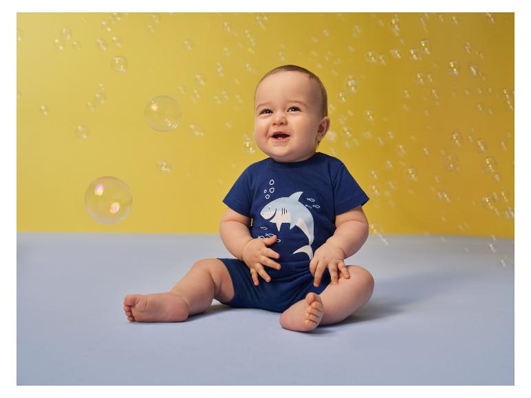 Bébé en short bleu Lupilu jouant avec des bulles.