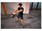 Homme en tenue de sport noire s'entraînant avec un kettlebell noir.