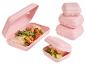Boîtes à lunch roses avec des wraps et des concombres, et une pile de boîtes fermées.