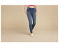 Une femme porte un jean skinny et des baskets Converse jaunes.